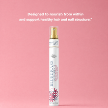 Bluegrass hair and nail spray bottle on a pink background with text about nourishing hair and nails.