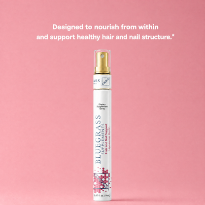 Bluegrass hair and nail spray bottle on a pink background with text about nourishing hair and nails.
