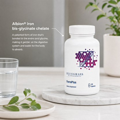 Supplement bottle labeled 'FerraPlus' by Bluegrass Supplements on a marble surface with water and a plant.