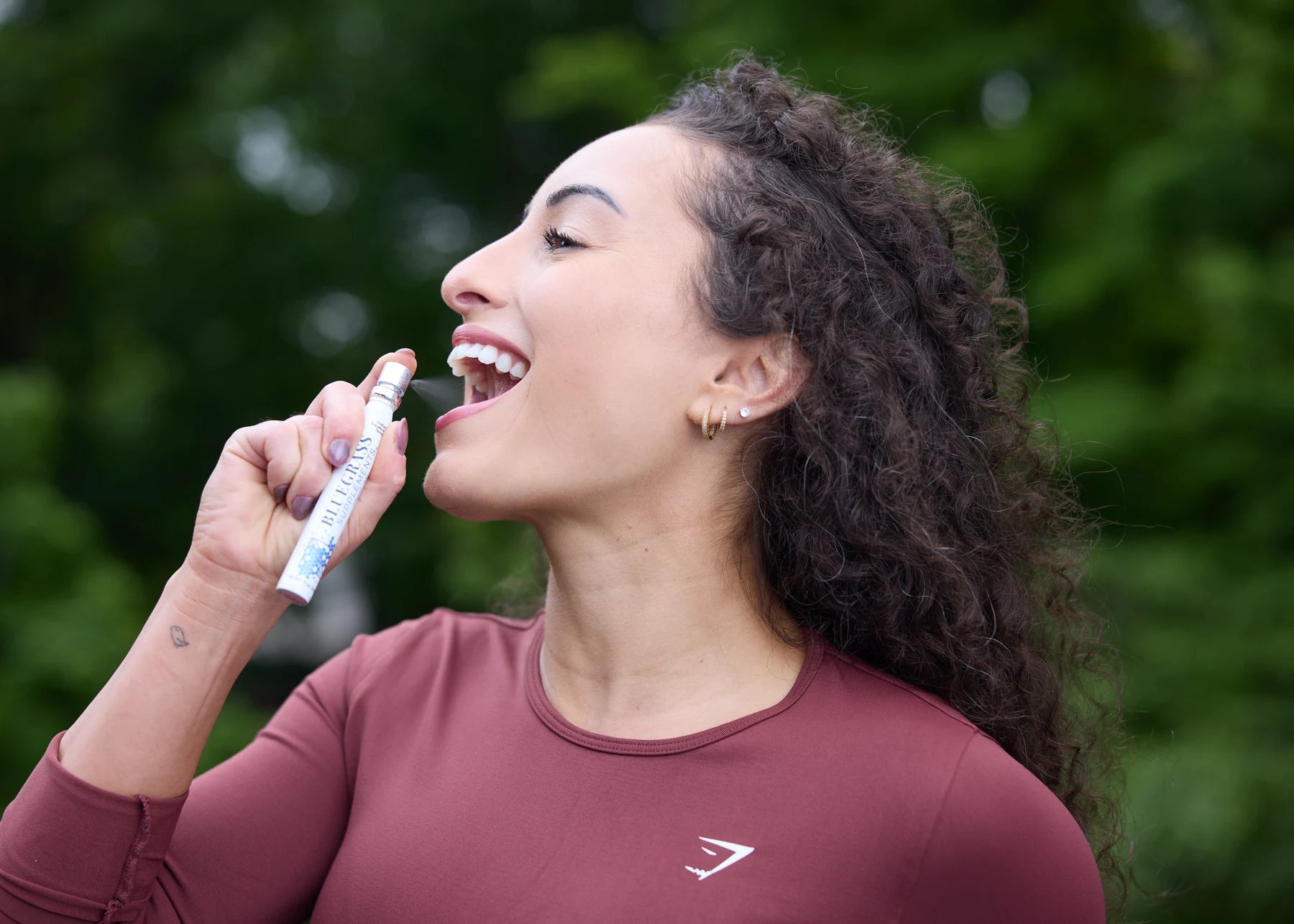 Woman using a Bluegrass vitamin spray outdoors